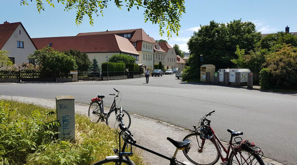 Das Bild zeigt einen Blick in den Dorfkern von Altdobritz von einer Grünfläche aus. Im Vordergrund befinden sich Fahrräder.