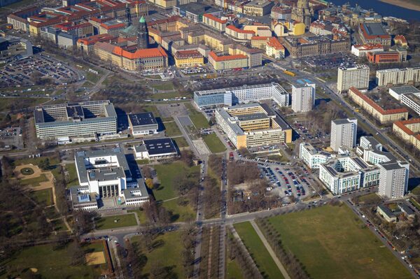 Auf einem Luftbild ist im Zentrum die Lingnerallee zu sehen. Im Umfeld ordnen sich baulich das Hygienemuseum, das Robotrongelände sowie am oberen Bildrand die innere Altstadt mit dem markanten Rathausturm ein.