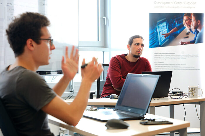 Zwei junge Männer diskutieren vor ihren Laptops zu einer Präsentation